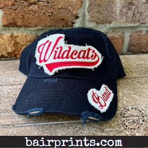 May include: Black distressed baseball cap with a white patch that says "Wildcats" in red lettering and a white heart patch that says "Band".