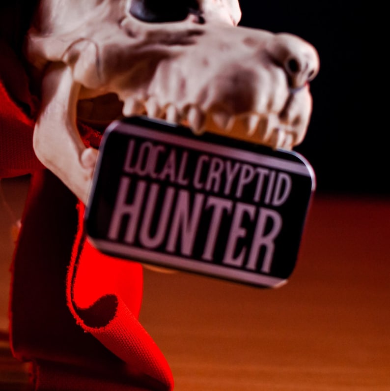 Local Cryptid Hunter and Local Cryptid badges being held against a skeleton model.