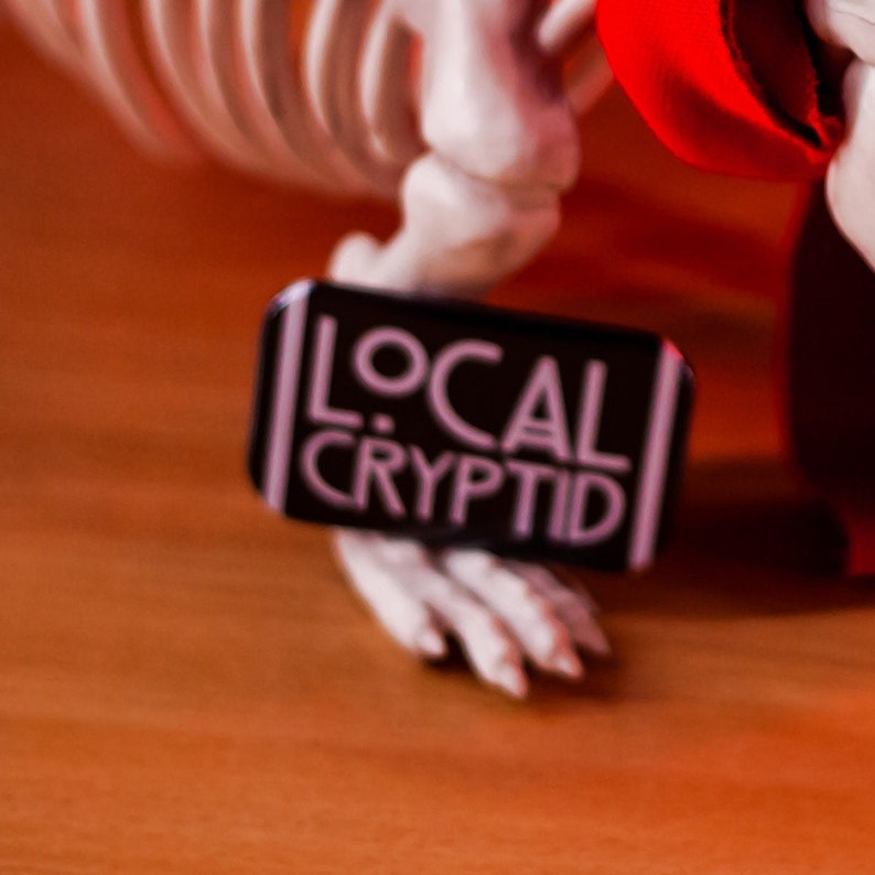 Local Cryptid Hunter and Local Cryptid badges being held against a skeleton model.