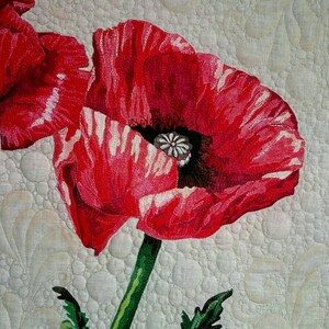 Può includere: Primo piano di un tessuto trapuntato con un vibrante fiore di papavero rosso. Il papavero ha accenti bianchi sui suoi petali e un centro scuro. Lo stelo e le foglie verdi contrastano con lo sfondo bianco sporco a motivi.