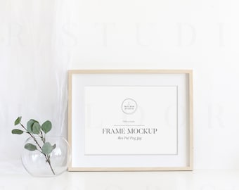 May include: A light wood frame mockup with a white mount and a white background. The frame is sitting on a white surface. The text "FRAME MOCKUP" is printed in black on the mount. The text "8x10" is printed in black below the text "FRAME MOCKUP".