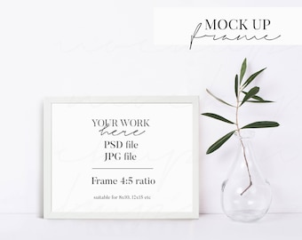 May include: White frame mockup with a white background. The frame is empty and has the text "YOUR WORK here PSD file JPG file Frame 4:5 ratio suitable for 8x10, 12x15 etc" inside. A small green plant is in a clear glass vase to the right of the frame.