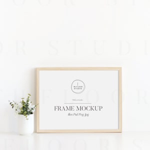 Puede incluir: Una maqueta de marco de madera clara con fondo blanco. El marco est&aacute; sentado sobre una superficie blanca. El texto "FRAME MOCKUP" est&aacute; escrito en texto negro en el marco. El texto "files Psd Png Jpg" est&aacute; escrito en texto negro debajo del texto "FRAME MOCKUP".