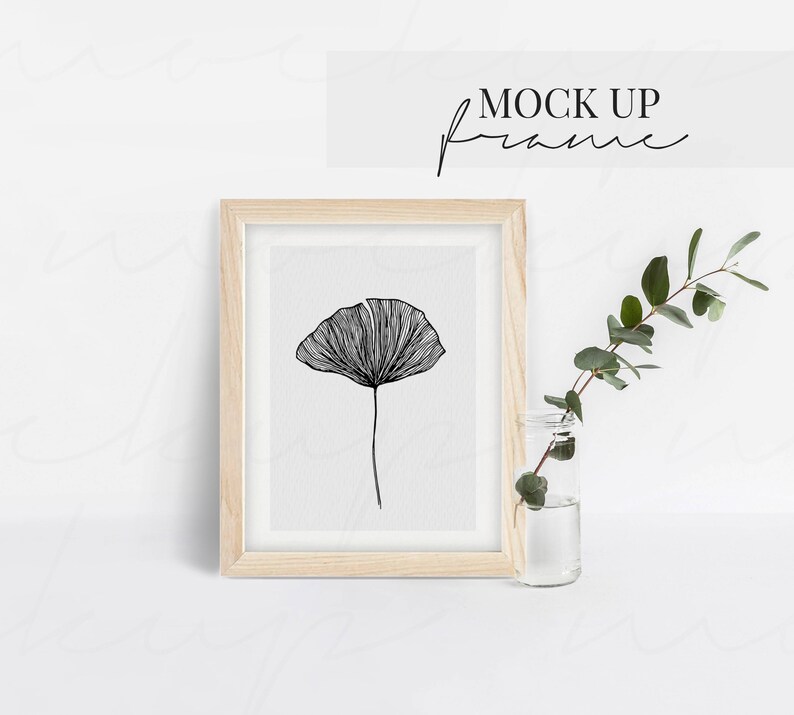 K&ouml;nnte beinhalten: Ein gerahmter schwarz-wei&szlig;er Kunstdruck mit einer detaillierten Strichzeichnung einer Blume. Das Kunstwerk befindet sich in einem hellen Holzrahmen. &Uuml;ber dem Rahmen steht der Text "MOCK UP frame". Neben dem Rahmen steht eine kleine Glasvase mit Gr&uuml;nzeug.