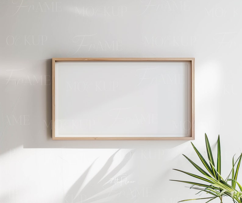 May include: A light wood frame with a white mat and a white background. The frame is hanging on a white wall with a green plant in the corner.