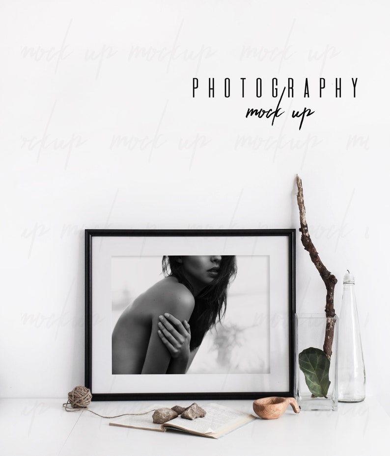 May include: Black and white photo of a woman in a black frame on a white surface with a wooden bowl, a book, and a vase with a branch and a leaf. The text "PHOTOGRAPHY mock up" is above the frame.