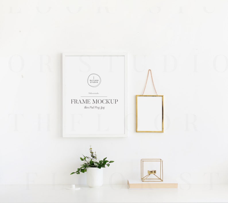 May include: White frame mockup with the text "FRAME MOCKUP" and the words "The Floor Studio" in a circle. A gold frame hangs from a chain on a white wall. A small gold candle holder and a potted plant are on a white table.