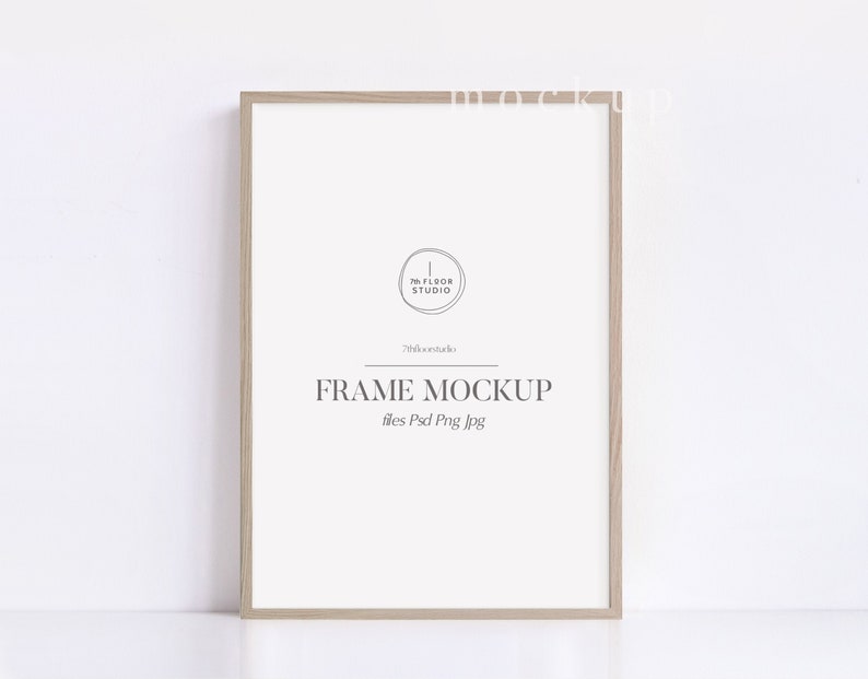 May include: A light brown wood frame mockup with a white background. The frame is on a white surface. The text "FRAME MOCKUP" is printed in gray on the white background. The text "files: Psd Png Jpg" is printed in gray below the text "FRAME MOCKUP".