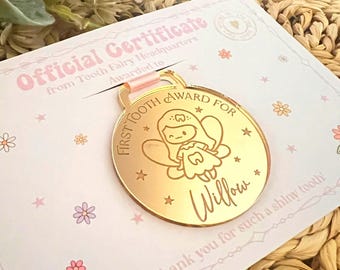May include: A gold-colored First Tooth Award medal with a fairy illustration and the name "Willow" engraved on it. The medal is on a certificate with the text "Official Certificate from Tooth Fairy Headquarters". The certificate has floral and star designs.