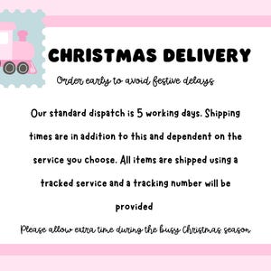 May include: A rectangular sign with a pink border and a light blue stamp-style corner featuring a pink train. The text reads: CHRISTMAS DELIVERY, Order early to avoid festive delays, Our standard dispatch is 5 working days, and more.