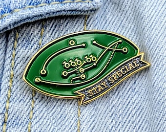 May include: Gold-colored enamel pin with a green football field design and the text "Stay Special".
