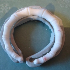 May include: A white silicone mould for making a resin bracelet in the shape of a bone. The mould is flexible and has a smooth surface.
