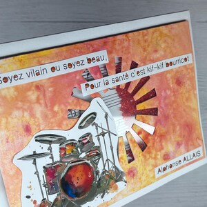 以下が含まれることがあります： オレンジとイエローの水彩画風の背景に、太陽の光のような切り抜き模様が施された長方形のグリーティングカード。前面にはドラムセットのイラストが重ねられており、「Soyez vilain ou soyez beau, Pour la santé c'est kif-kif bourricot, Alphonse ALLAIS」というテキストが記載されています。