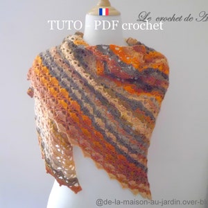 Peut inclure: Un châle en crochet dans des tons d'orange, de brun et de beige. Le châle est présenté sur un mannequin blanc. Le texte "TUTO - PDF crochet" est visible en haut de l'image.