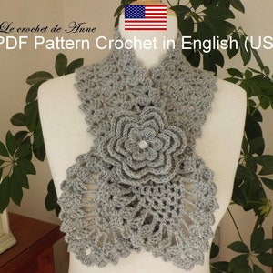 Peut inclure: Un collier en crochet gris avec un grand motif de fleur. Le collier est sur un mannequin blanc. Le texte "Le crochet de Anne PDF Pattern Crochet in English (US)" est en haut de l'image.