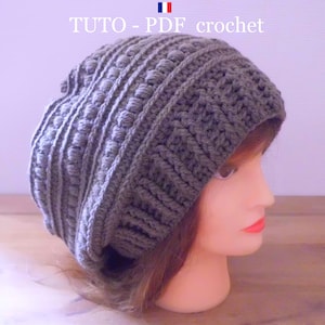 Peut inclure: Un bonnet en crochet gris avec un motif texturé. Le bonnet est ample et a un bord rabattable.