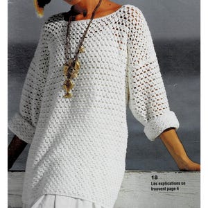 Peut inclure: Top en crochet blanc à la coupe ample et au col bateau. Le haut est orné d'un motif en crochet avec un design carré. Le mannequin porte un long collier avec plusieurs breloques.