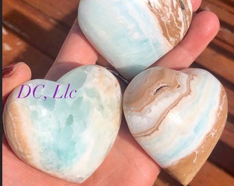 May include: Three heart-shaped blue and brown calcite crystals. The crystals are polished and have a smooth, shiny surface.