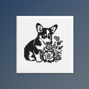 May include: A square white tile featuring a high-contrast black graphic illustration of a Corgi puppy sitting next to a cluster of detailed flowers. The design is centered on the tile, showcasing the dog's pointed ears and markings.