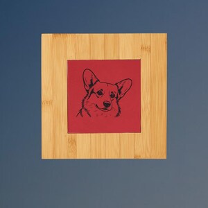 May include: A square bamboo frame surrounding a central red tile. The tile features a black line art illustration of a Corgi dog head, showing the animal's pointed ears, alert eyes, and snout in a detailed, minimalist graphic style.