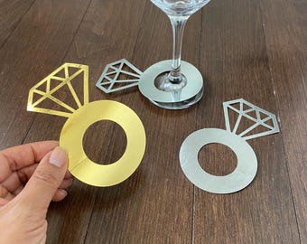 May include: Two gold and silver ring-shaped wine glass charms with a diamond design. The charms are perfect for a wedding or engagement party.