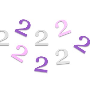 May include: A collection of eight paper cut-out numbers, all in the shape of the number two. The numbers are in three different colors: purple, pink, and light gray.