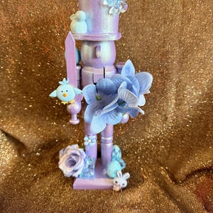 Puede incluir: Un letrero de madera hecho a mano con el texto "Bienvenido" en un estilo manuscrito. El letrero está pintado de blanco con un acabado envejecido, y una pequeña hoja verde está sujeta en la parte superior. El letrero mide aproximadamente 30 cm de ancho.