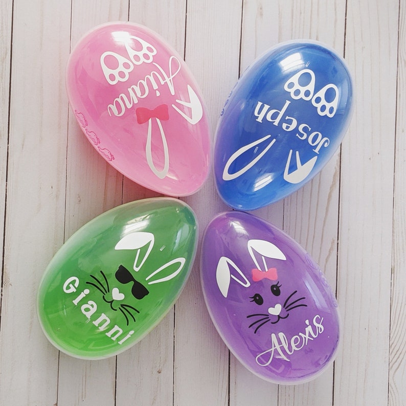 May include: Four clear plastic Easter eggs with bunny designs and personalized names. The eggs are pink, blue, green, and purple.