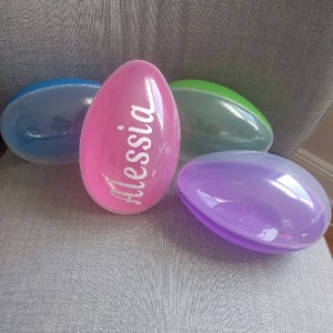 May include: Four plastic Easter eggs, one pink with the name "Alessia" written on it, one blue, one green, and one purple.
