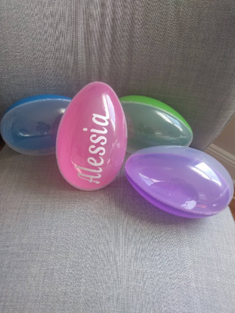 May include: Four plastic Easter eggs, one pink with the name "Alessia" written on it, one blue, one green, and one purple.