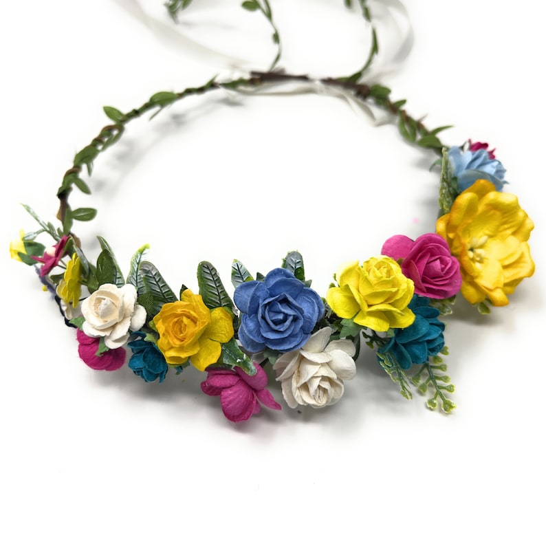 May include: A colorful flower crown with yellow, blue, pink, and white paper flowers. The crown is made of a brown vine base with green leaves.