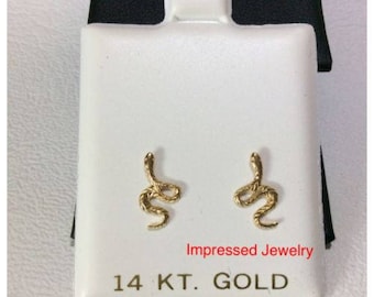 May include: A pair of gold snake earrings on a white background. The earrings are 14 karat gold and are displayed in a small jewelry box. The box has the text "Impressed Jewelry" and "14 KT. GOLD" printed on it.