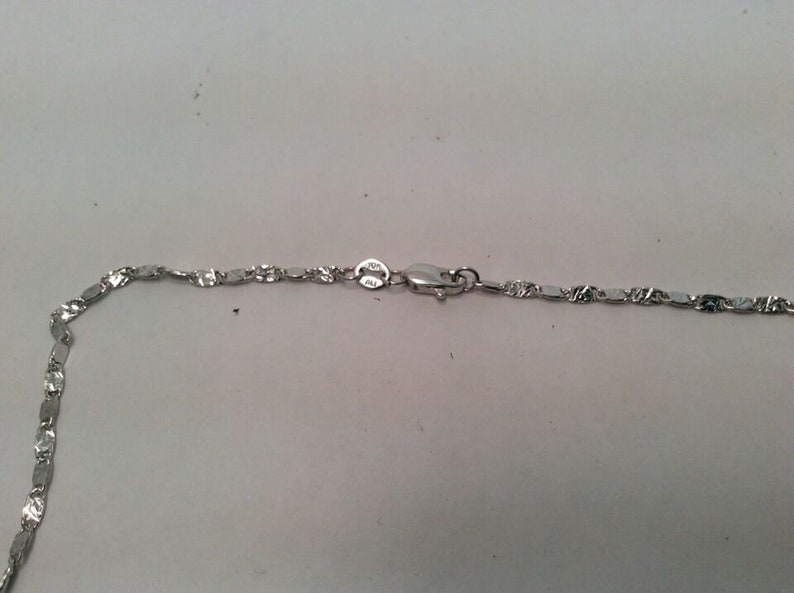 May include: A silver chain necklace with a lobster clasp. The chain is made of small, flat, oval links.