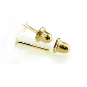 May include: A pair of gold-toned earring backs. The backs are round and have a smooth surface.