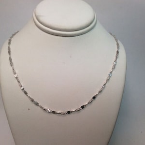 May include: A silver chain necklace with a delicate, flat link design.