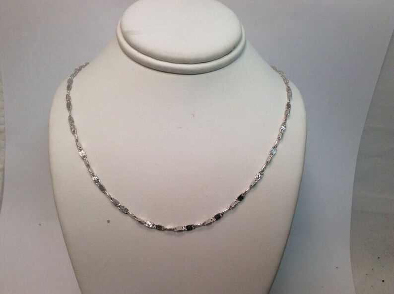 May include: A silver chain necklace with a delicate, flat link design.