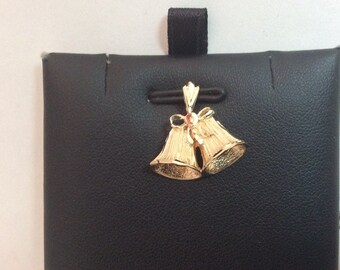 May include: A gold-tone pendant charm featuring two bells tied together with a bow. The bells are detailed with a textured surface.
