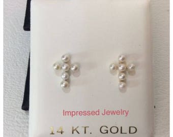 May include: A pair of gold cross earrings with white pearl accents. The earrings are displayed on a white card with the text "Impressed Jewelry 14 KT. GOLD".