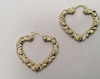 May include: A pair of gold heart-shaped hoop earrings. The earrings are made of a twisted rope design with small hearts along the edge.