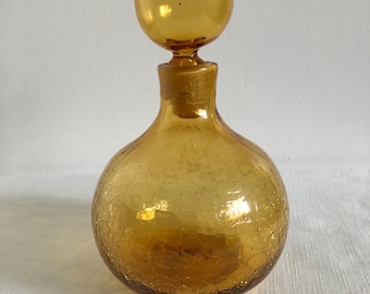 May include: Amber glass bottle with a textured surface and a round, amber glass stopper. The bottle is a decorative piece.