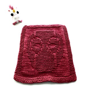 May include: A burgundy knitted dishcloth with a decorative pattern in the center. The dishcloth is made of cotton yarn and is designed to be absorbent and durable.