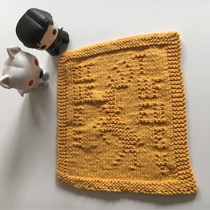 May include: A yellow knitted dishcloth with the words "Winter is Coming" in a white knitted pattern.