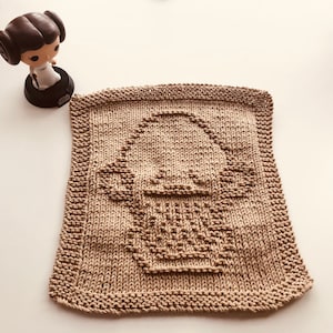 May include: A brown knitted dishcloth with a raised design of a Star Wars character's head.