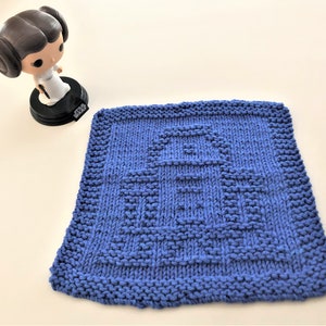 Könnte beinhalten: Ein blauer Strick-Geschirrtuch mit einem weißen Roboter-Design. Das Geschirrtuch ist quadratisch und hat eine strukturierte Oberfläche.