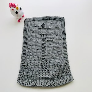 May include: A grey knitted dishcloth with a simple design. The dishcloth is made with a textured stitch and has a subtle pattern.
