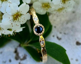 Anillo de compromiso en oro de 18 quilates, diamante negro y dos diamantes blancos.