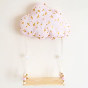 Peut inclure: Un coussin en forme de nuage rose avec un imprim&eacute; d'oiseaux dor&eacute;s suspendu &agrave; une ficelle blanche avec des perles en bois et une petite &eacute;tag&egrave;re en bois.