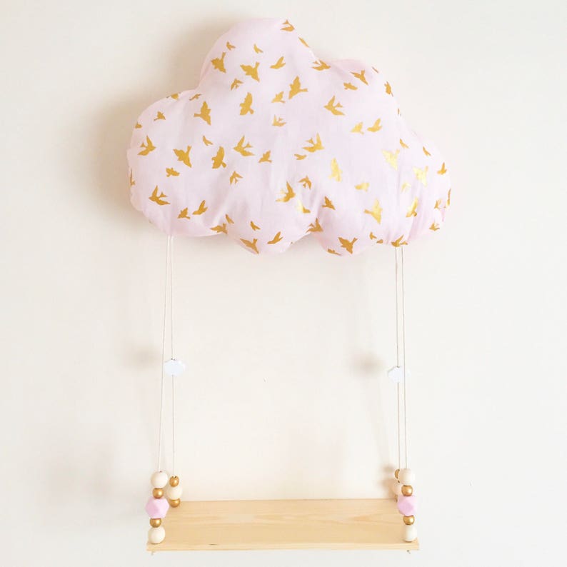 Peut inclure: Un coussin en forme de nuage rose avec un imprim&eacute; d'oiseaux dor&eacute;s suspendu &agrave; une ficelle blanche avec des perles en bois et une petite &eacute;tag&egrave;re en bois.
