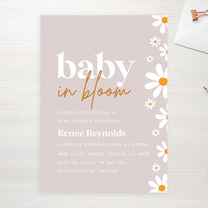 May include: A light purple baby shower invitation with white daisies with yellow centers along the right side. The text reads "baby in bloom" in white and orange lettering. The invitation includes the date, time, location, RSVP information, and registry information.