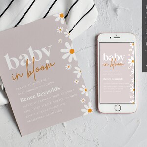May include: A baby shower invitation with a light pink background and white daisies. The text "baby in bloom" is in orange and white. The invitation includes the name "Renee Reynolds" and details for the shower.